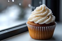 Chocolate cupcake with cream frosting and gold wrapper displayed on windowsill with snowy winter background, perfect for bakery, dessert, and food photography projects.