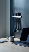 Modern workspace with organized cables hanging on wall mount next to laptop and coffee cup on wooden desk for office productivity and cable management.