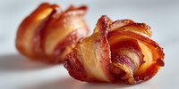Crispy bacon-wrapped scallops with golden caramelized edges on white background, gourmet seafood appetizer for restaurant menu and culinary photography.