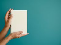 Hands holding blank white card against turquoise background, suitable for mockups, advertising campaigns, and promotional designs.