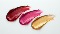 Three glossy lipstick smear swatches in red, pink, and gold on white background, showcasing rich pigment textures for beauty and cosmetic design.
