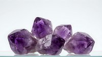 Raw amethyst crystal cluster with natural purple gemstone formations on white background isolated for jewelry and healing stone designs.