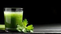 Fresh green celery smoothie in glass with raw celery stalk and leaves on dark background, healthy detox drink for weight loss and cleansing.