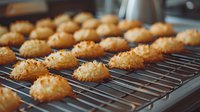 Golden coconut macaroons cooling on metal baking rack, fresh from oven with crispy toasted exterior and soft interior, homemade sweet treats for dessert or holiday baking.