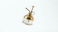 Brass oil lamp with glass base and curved spout for pouring, featuring vintage design elements suitable for home decor, antique collections, or historical product photography.