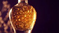 Luxury golden liquid in glass bottle with sparkling particles, ideal for perfume, cosmetics, or premium product packaging and branding.