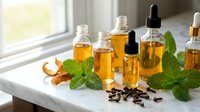 Natural essential oils in amber glass bottles with droppers on white windowsill, fresh mint leaves and spices for aromatherapy and wellness treatments.