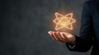 Businessman holding glowing atomic symbol in open palm representing nuclear energy, science innovation and molecular research concepts for technology presentations.