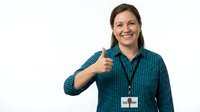 Young woman with dark hair and fair complexion wearing blue checkered shirt and ID badge giving thumbs up gesture against white background for corporate and professional use.