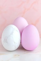 Marble white and pink pastel eggs on soft rose background with delicate marble texture, minimal Easter composition for greeting cards and social media posts.