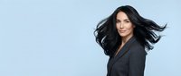 Professional businesswoman with flowing dark hair in black blazer against light blue background for corporate branding and marketing materials.