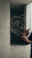 Hands creating glowing golden energy sphere with swirling light trails in modern interior space for technology and innovation concepts.