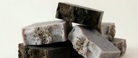 Handmade charcoal and natural soap bars stacked together, featuring organic textures and earthy tones for skincare, wellness, and beauty product marketing.