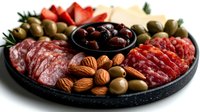 Gourmet charcuterie board with salami, olives, nuts and cheese arranged on dark slate platter for entertaining and appetizer presentations.