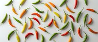 Colorful hot chili peppers scattered on white background. Fresh spicy vegetables in red, green, yellow and orange colors for cooking and seasoning.