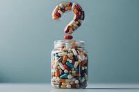 Pills and capsules forming question mark shape above glass jar filled with various medications on blue background, healthcare concept medical uncertainty.