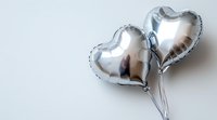 Silver heart-shaped foil balloons against white background, romantic celebration decor with soft shadows and reflective metallic surface. Suitable for wedding and love themes.