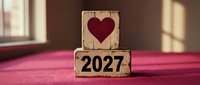 Heart symbol and 2027 year number on wooden blocks stacked on pink surface, representing new year resolutions, love goals, and future planning for romantic occasions.