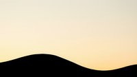 Silhouette of rolling hills against warm golden sunset sky, creating serene landscape horizon for nature and travel designs.