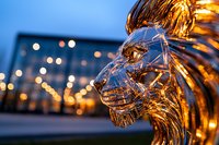 Crystal glass sculpture of human profile against blurred city lights background creates dramatic artistic composition with golden bokeh effect.