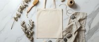 Blank cotton tote bag mockup with eucalyptus branches and natural accessories on marble surface for branding and design projects.
