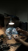 Hands holding glowing digital brain with neural network connections in workshop setting with tools and warm lighting for technology concepts.