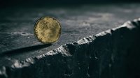 Glowing golden sphere resting on dark textured surface with dramatic lighting and moody atmosphere, suitable for conceptual and artistic projects.