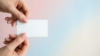 Caucasian woman holding blank white business card against soft pastel gradient background for branding and corporate identity mockup purposes.