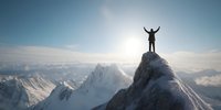 Silhouette of person with raised arms standing on snowy mountain peak against backdrop of majestic mountain range and bright sun in clear blue sky.