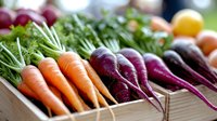 Fresh organic vegetables display with colorful carrots, beets and leafy greens arranged at farmers market for healthy cooking and nutrition concepts.