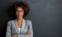 Confident African American businesswoman with glasses and curly hair standing against dark background with arms crossed, portraying leadership and professionalism.