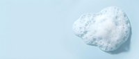 Fluffy white soap foam or shaving cream blob isolated on light blue background, ready for cosmetic, hygiene, and skincare design projects.