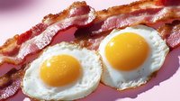 Crispy fried bacon strips alongside sunny side up eggs with bright yellow yolks and white edges on pink background, classic breakfast combination.