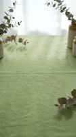 Soft green linen textile background with eucalyptus branches and ceramic vases creating natural home decor atmosphere for product photography and branding.