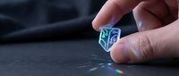 Caucasian male hand holding glowing holographic cube with digital data visualization on dark surface for technology and innovation concepts.