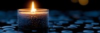 Single glowing candle with water droplets on glass holder against dark blue background creates peaceful spa atmosphere for wellness and meditation.