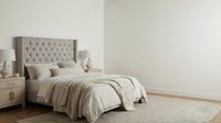 Spacious bedroom interior with upholstered headboard, neutral bedding, wooden nightstands, and minimalist decor for home design and real estate marketing.