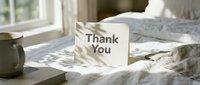 Thank You card standing on a cozy bed with soft linen, morning light, and a mug nearby, creating a warm, heartfelt atmosphere.