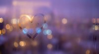 Heart shape drawn on foggy glass window with warm bokeh lights creating romantic atmosphere for Valentine's Day celebrations and love concepts.