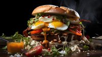 Gourmet burger with fried egg, bacon, fresh vegetables and melted cheese on dark background with steam rising, dramatic food photography style.
