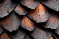 Weathered wooden shingles in dark brown and copper tones create dramatic pattern of overlapping scales with deep shadows and textural detail. Natural aging effect.