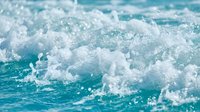 Turquoise ocean waves crashing with white foam and water splashes creating dynamic seascape motion for summer vacation and coastal lifestyle concepts.