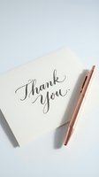 Elegant thank you card with handwritten calligraphy script on cream paper with rose gold pen for gratitude expression and correspondence.