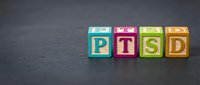 Post-traumatic stress disorder concept represented by colorful wooden blocks with letters spelling PTSD on dark slate background for mental health awareness and psychology education.