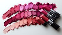 Vibrant lipstick swatches in shades of pink and red with crushed powder texture and metallic tubes arranged on white background, isolated cosmetic product photography.