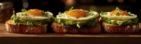 Open-faced avocado toast with soft poached eggs, fresh herbs and red caviar served on rustic bread against dark background with bokeh lights.