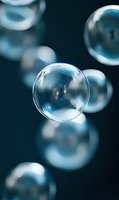 Floating transparent spheres with reflective surfaces against a dark teal background, featuring shallow depth of field for scientific, abstract, or design applications.