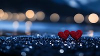 Two red glitter hearts on dark reflective surface with romantic bokeh lights in background creating dreamy Valentine's Day atmosphere.