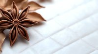 Star anise pod on white marble surface with soft brown fabric, creating elegant contrast and texture for culinary and spa concepts.