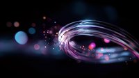 Glowing spiral light trail with pink and blue bokeh effects on dark background creates magical atmosphere for abstract design projects.